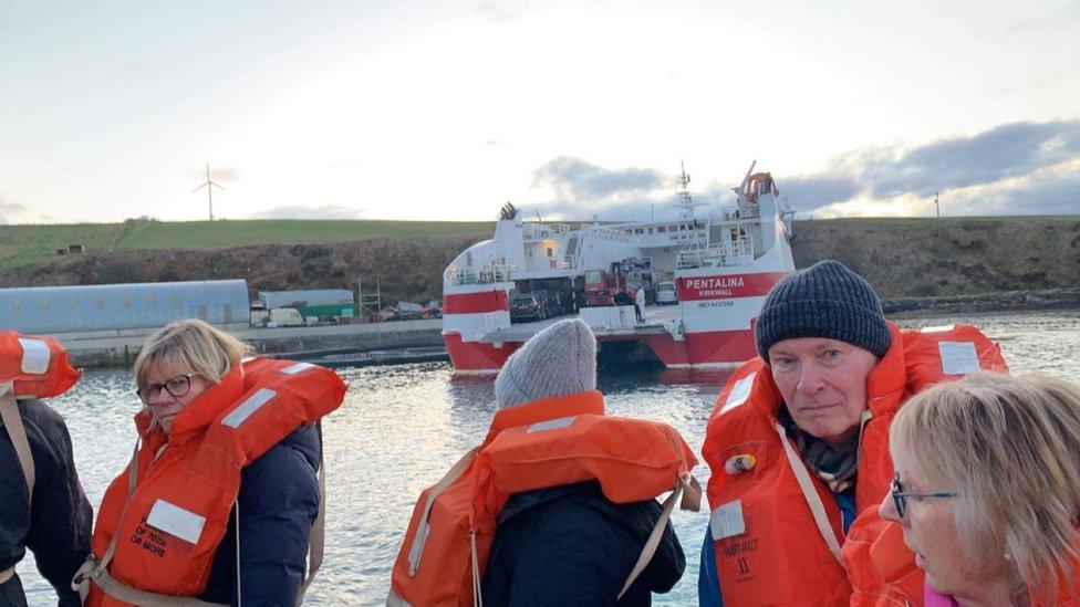 Passengers on lifeboat with ferry in background