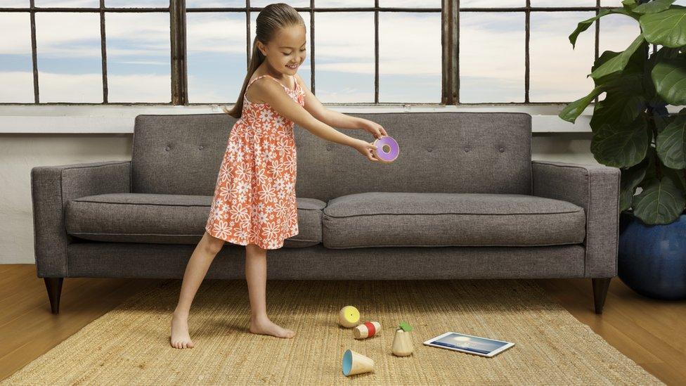 Young girl playing with wooden toys and tablet computer