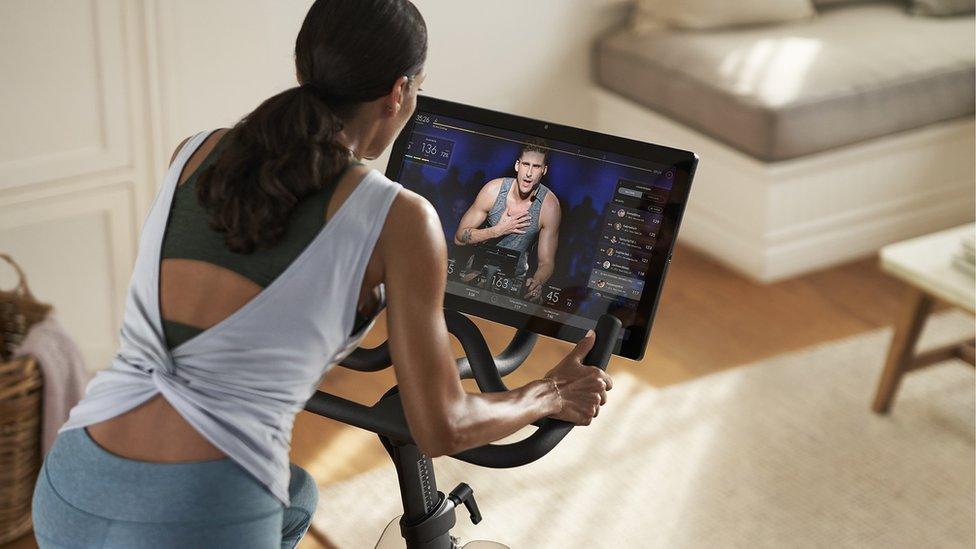 A woman uses a Peloton stationary bike