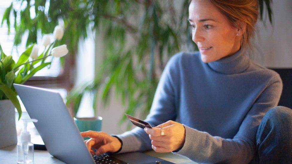 A woman sitting at a computer using a payment card