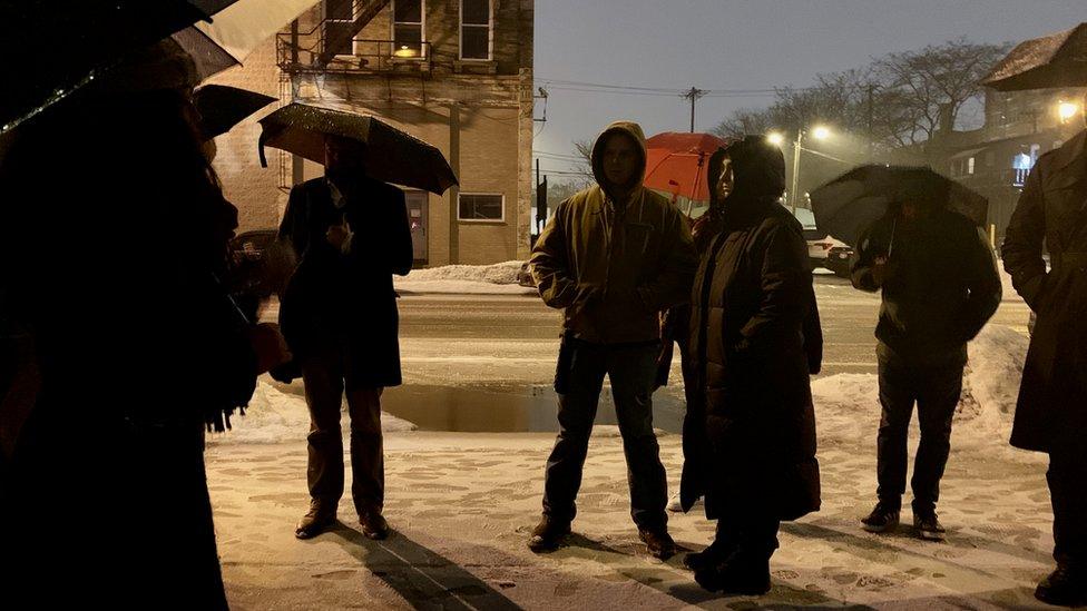 People on tour gather under umbrellas in an alleyway