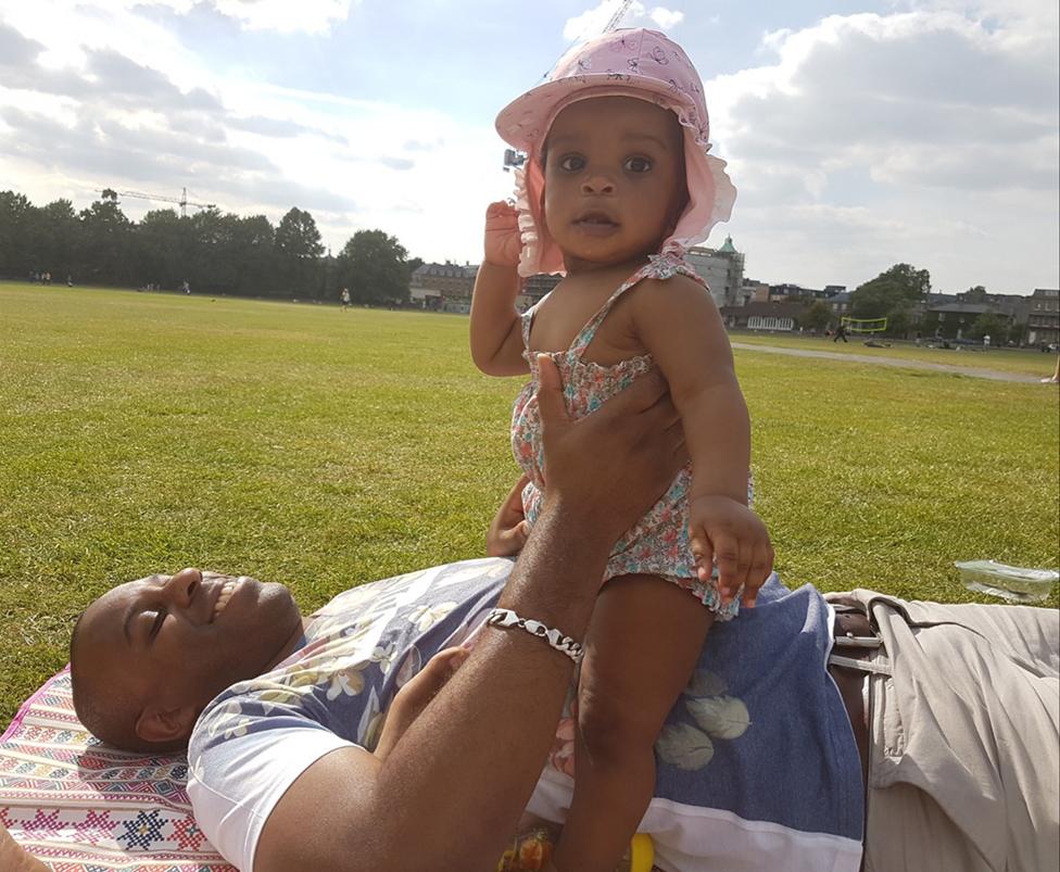 Elliott lying on the grass with his daughter sitting on his belly