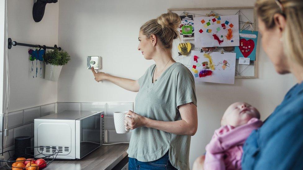 Woman adjusting a thermostat