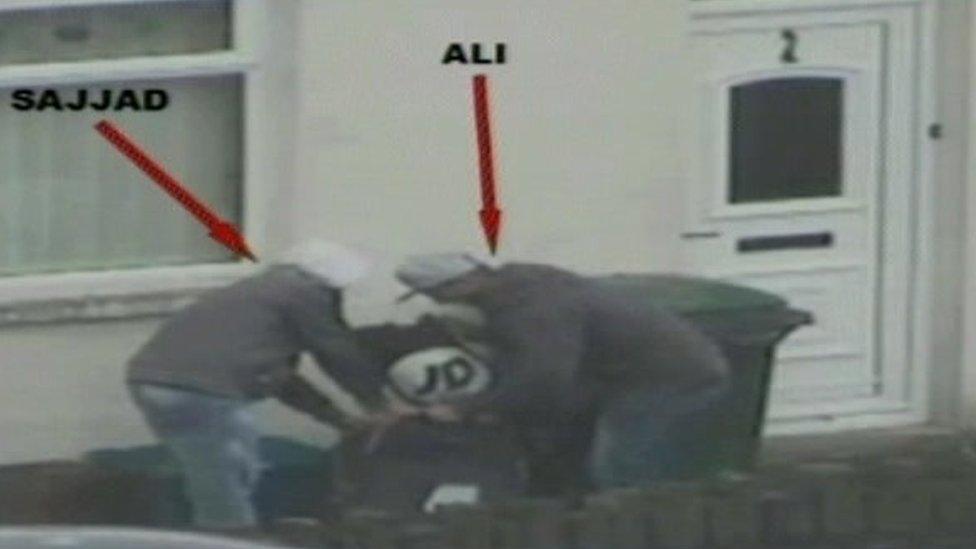 Police surveillance image of Imtiaz Ali and Mohammed Sajjad removing a black sports bag from a blender box and placing it in a black suitcase