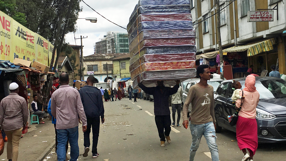 A man carrying mattresses on his head along a street in the Bole-Mikael neighbourhood of Addis Ababa in Ethiopoia