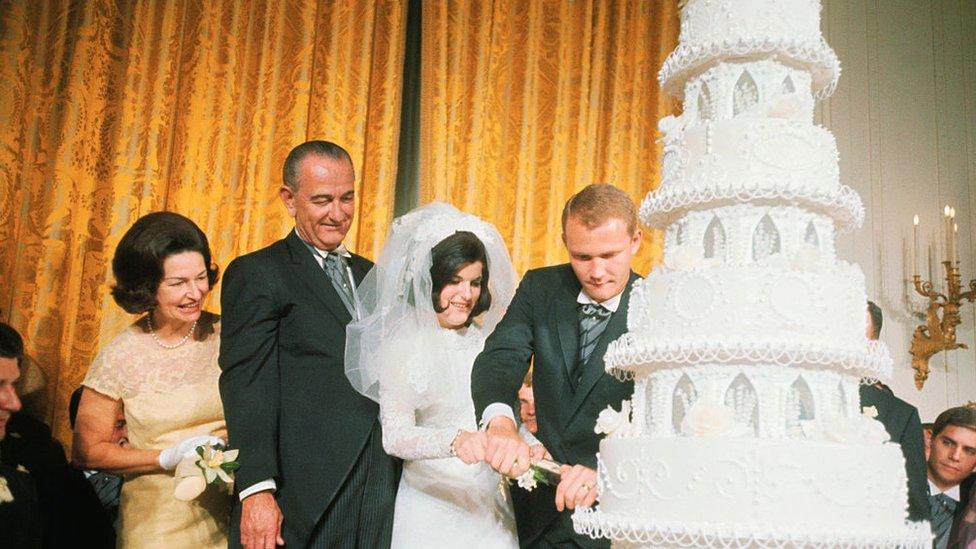 Lyndon and Claudia Johnson watch their daughter cut her wedding cake