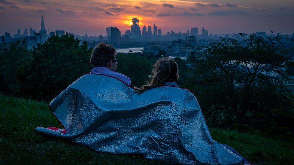 A couple wrapped up in a blanket as the sun sets from Greenwich Park, London, on Sunday