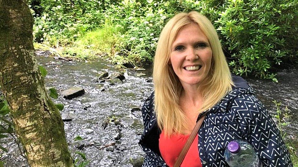 Denise Jarvis standing on a riverbank smiling