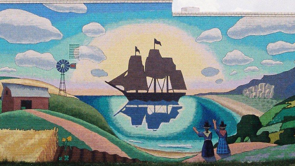 Great Plains Welsh Heritage Centre mural showing a masted ship in a harbour with women in Welsh traditional hats and dresses waving