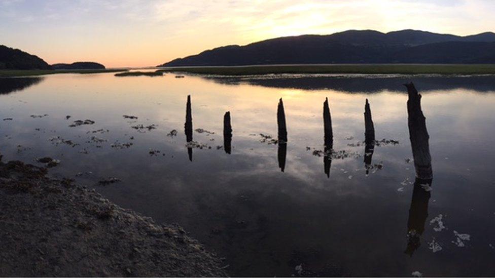 An old, sunken jetty at sundown across the Mawddach Estuary