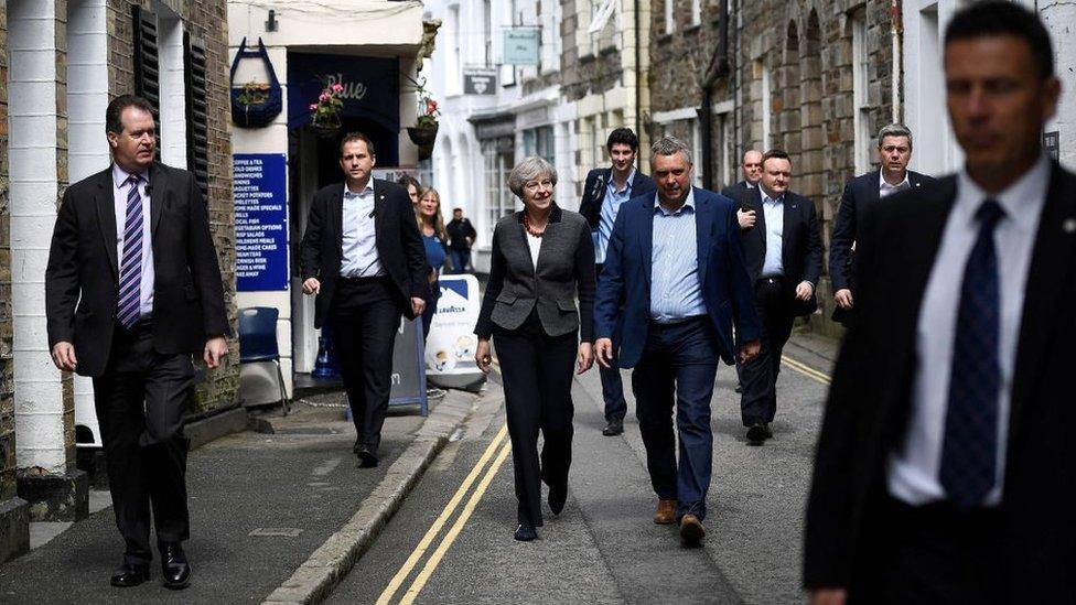 Britain's Prime Minister Theresa May (C) is flanked by security guards as she walks in Mevagissey, south-west England, during the 2017 election campaign