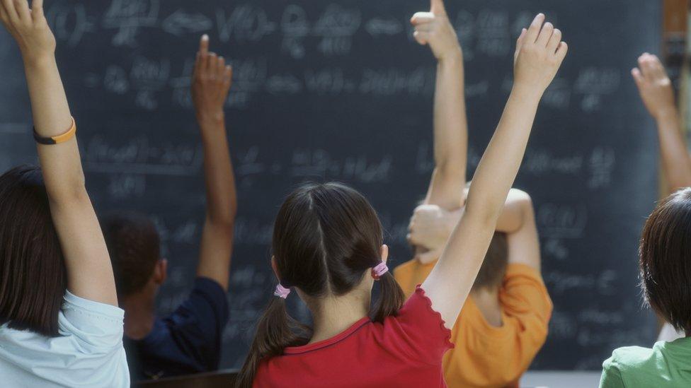 kids-in-classroom-with-hands-up