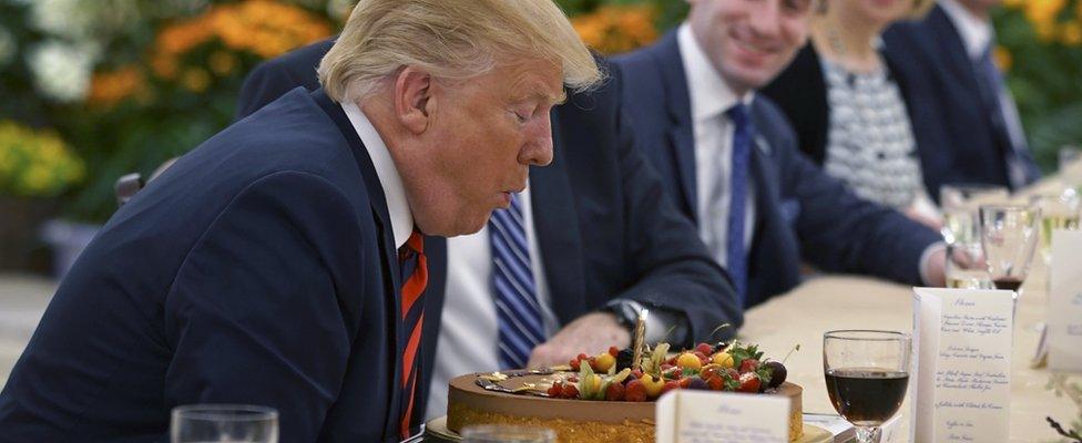 Donald J. Trump (L) blowing out the candle of a birthday cake