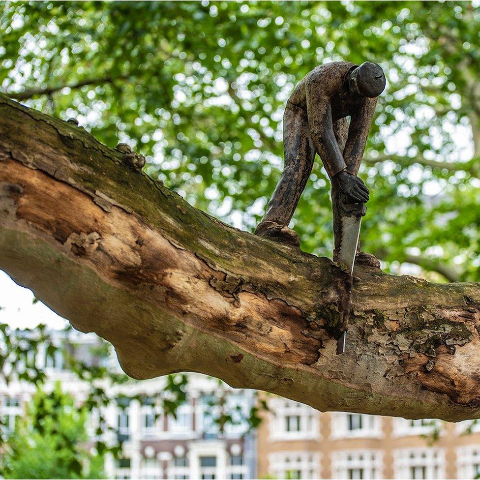 Sculpture of man sawing a branch