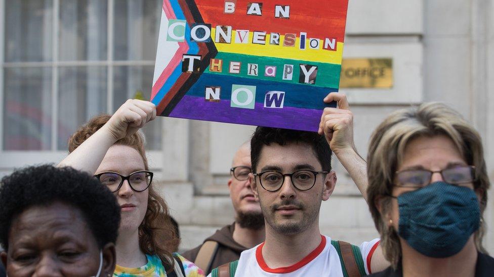 Protestors with sign saying ban conversion therapy now