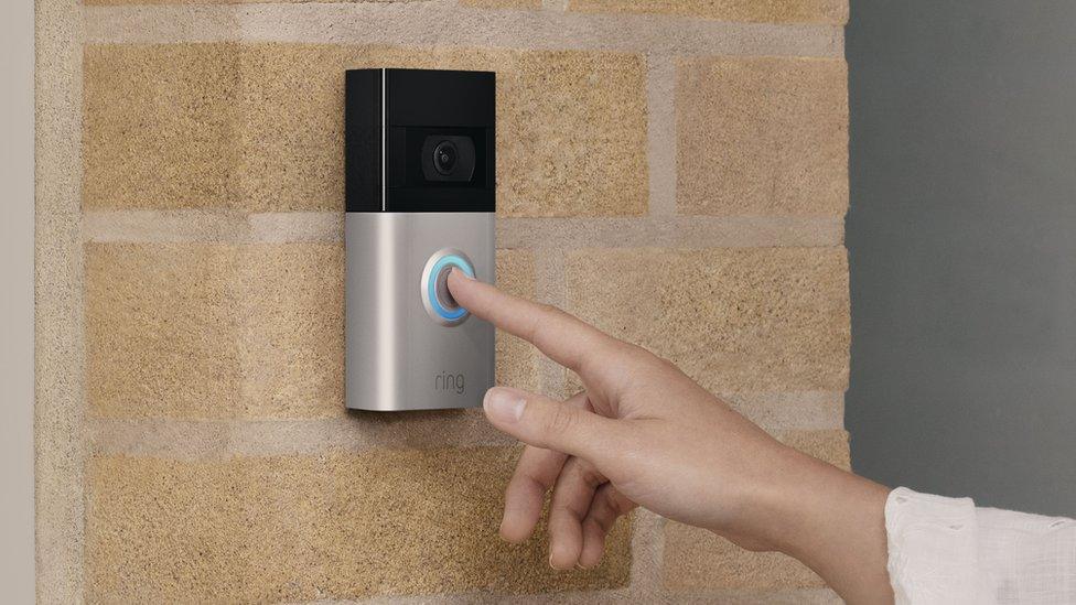 A finger pushing the button on a ring doorbell