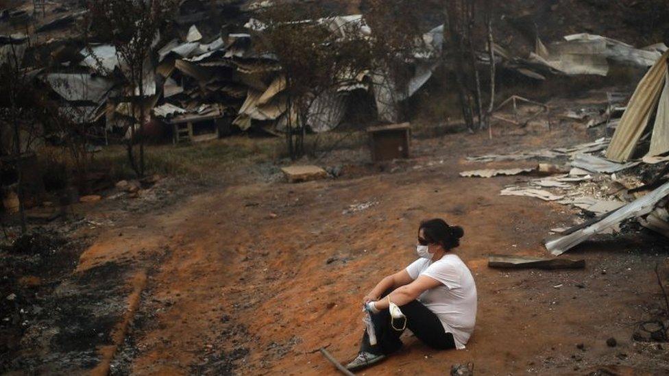 A woman takes a break while working to clean up the debris after a forest fire devastated Santa Olga, 240 kilometres south of Santiago, on January 26, 2017.