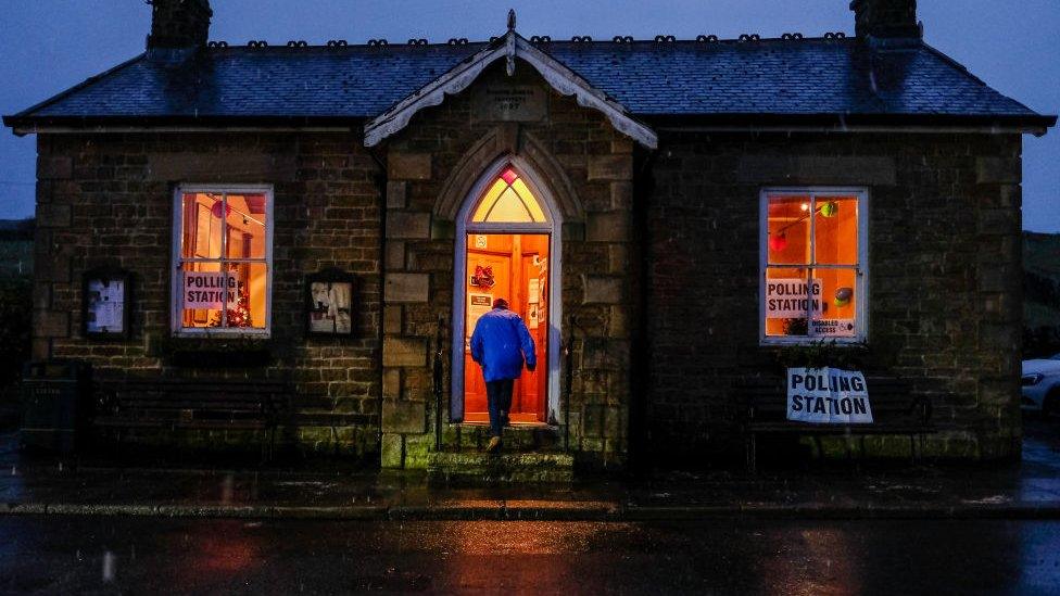 A man enters a polling station as snow falls in the North Pennines