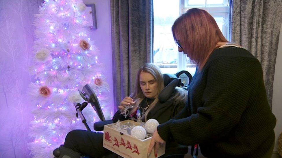 Angel and her mum decorate a Christmas tree