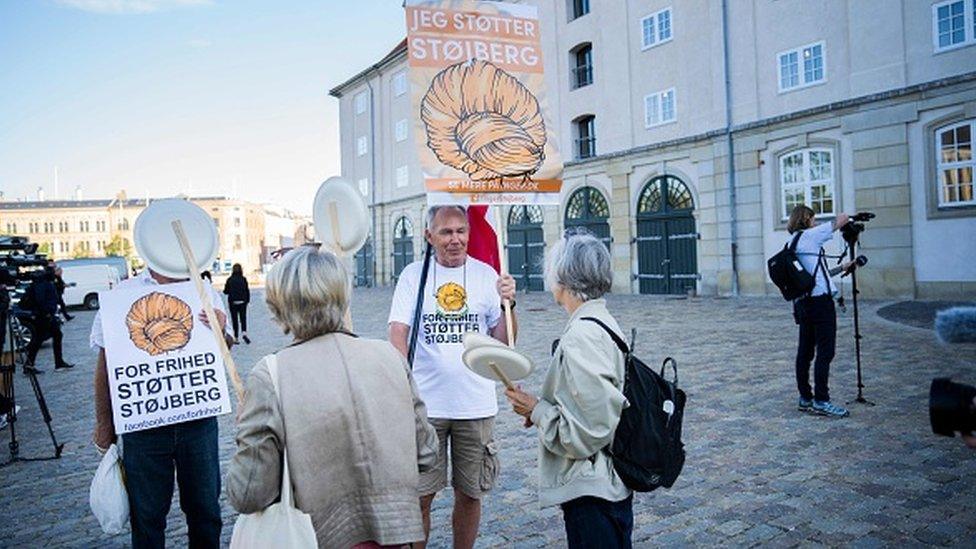 Demonstrators hold up posters in support of former Danish Immigration Minister Inger Stoejberg