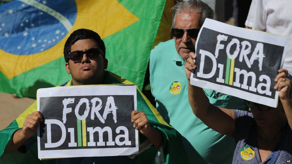 Demonstrators hold signs that read in Portuguese "Dilma Out" during a protest against the government on 16 August 2015