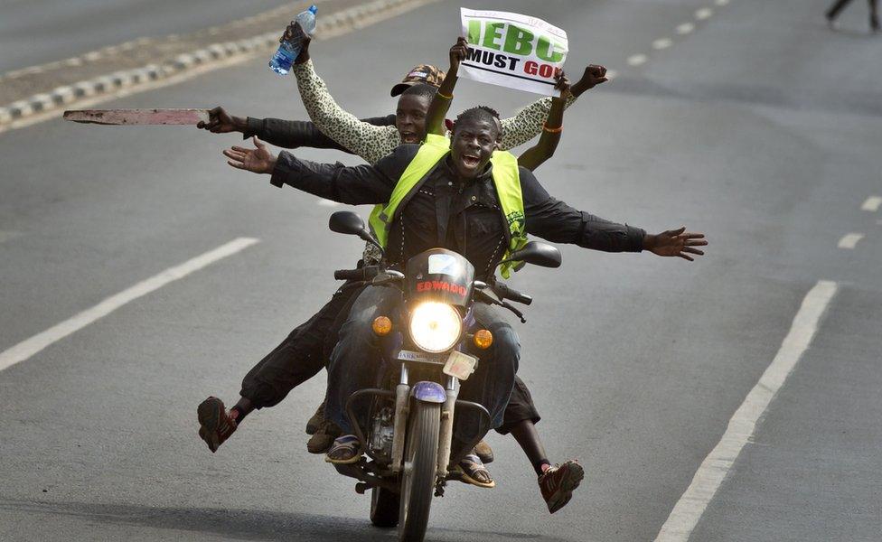 A motorcycle carrying protesters holding a placard using the acronym of the national electoral commission, drives ahead of demonstrators on foot calling for the disbandment of the commission over allegations of bias and corruption, in downtown Nairobi, Kenya Monday, June 6, 2016. While demonstrations led by opposition leaders in the capital were largely peaceful, police in the western town of Kisumu tear-gassed demonstrators who responded by throwing stones and witnesses say some people were killed by police. (AP Photo/Ben Curtis)