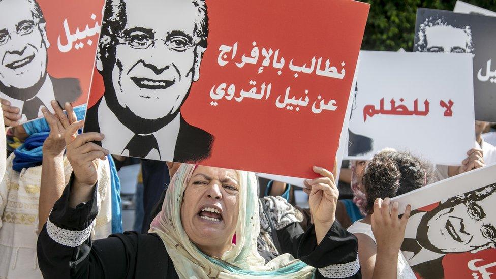 Supporters of presidential candidate Nabil Karoui carry placards as the protest over his imprisonment