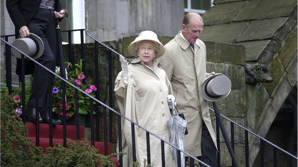 The Queen checks for rain as she attends a garden party at the palace of Holyroodhouse in Edinburgh during her Golden Jubilee year visit.