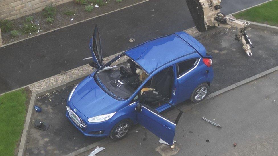 Damaged car with doors thrown open and windows blown out