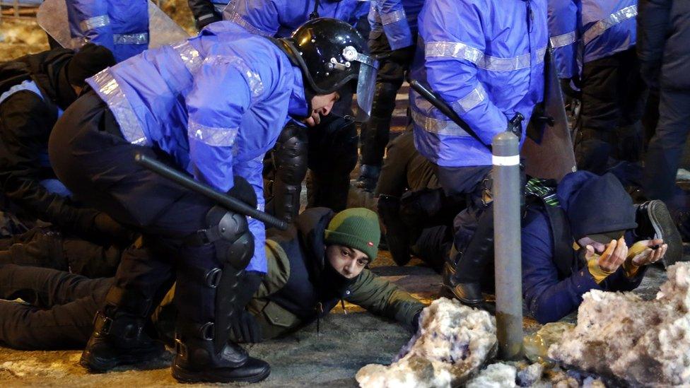 Young protesters lay on the pavement with the hands on their head after being arrested by the riot police at the end of a protest rally in front of government headquarters in Bucharest, Romania