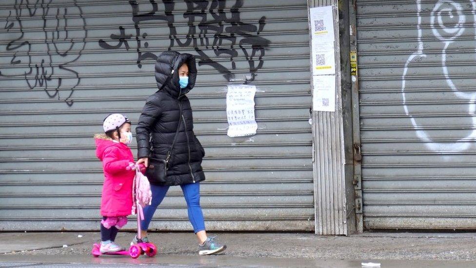 a woman in NY walks past a closed store