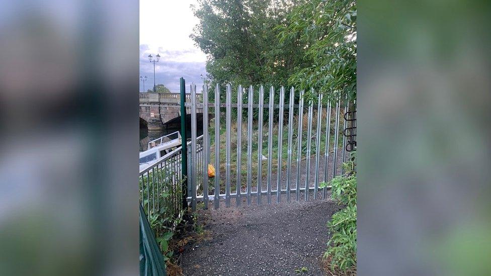 Fenced-off footpath, with bridge in the distance