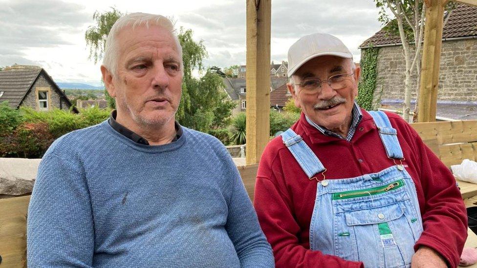 On the left is Steve Hutchings wearing a blue jumper and on the right is Brian Chislett wearing a red jumper and denim dungarees.