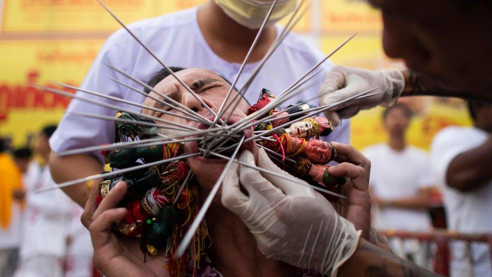 Devotee has multiple skewers pierced through his cheeks