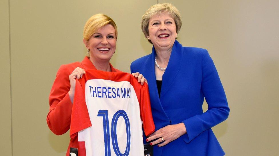 Croatia President Kolinda Grabar-Kitarovic (L) offering a Croatia national football team jersey to British Prime minister Theresa May (R) at the NATO headquarters in Brussels