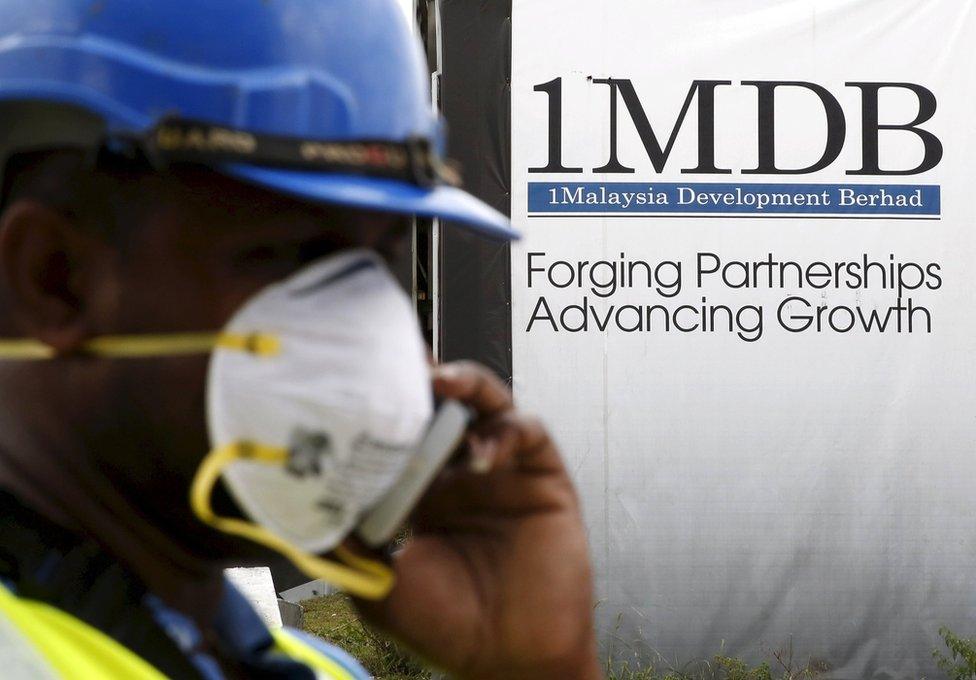 A construction worker talks on the phone in front of a 1Malaysia Development Berhad (1MDB) billboard at the Tun Razak Exchange development in Kuala Lumpur, Malaysia, in this 3 February 2016 file photo