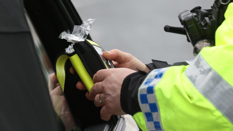 A police officer looking at a breathalyser