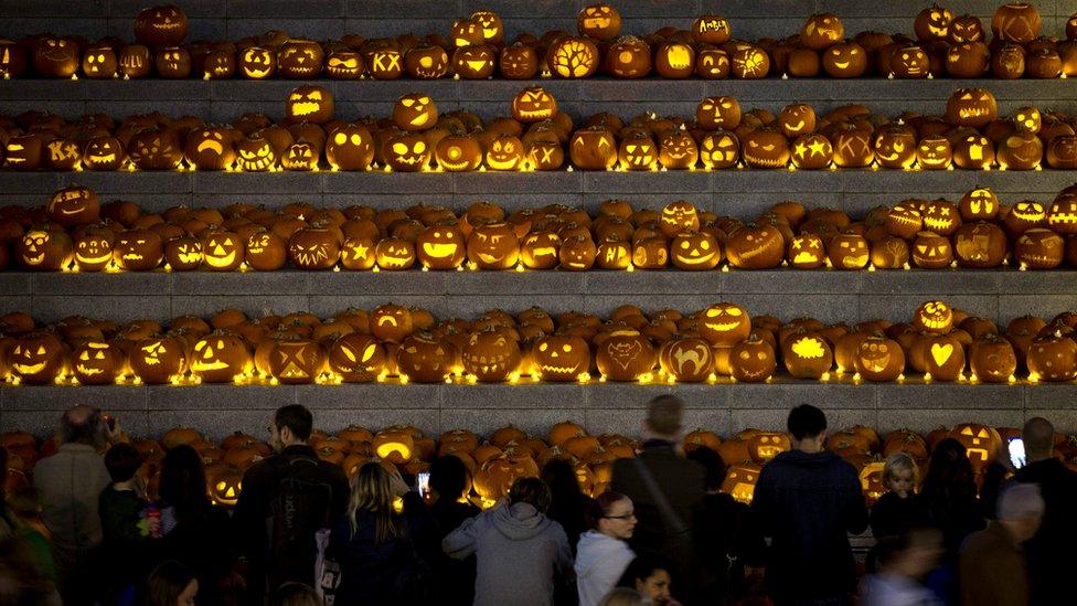 Hundreds of jack-o'-lanterns sat on some stone steps as people look and take photographs.