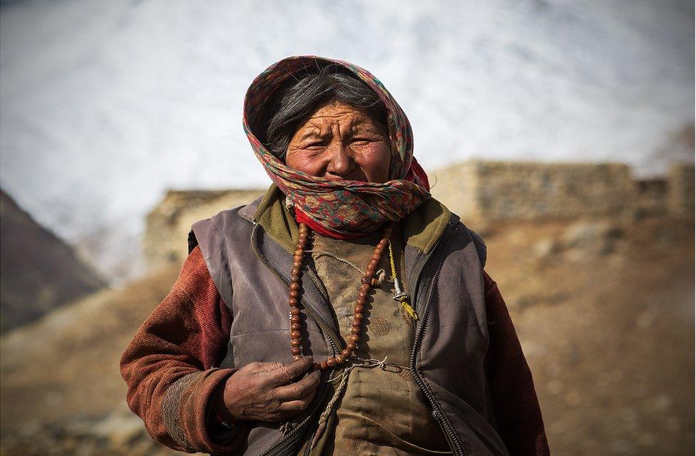 A woman stands wrapped up in many layers of clothing