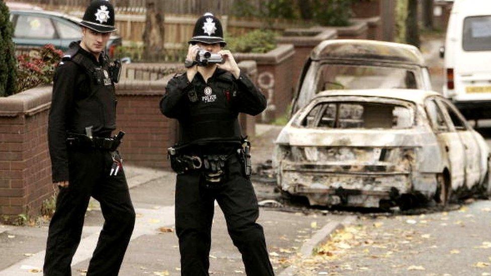 Police investigate the area near burnt out vehicles in Lozells on October 23, 2005 in Birmingham, England