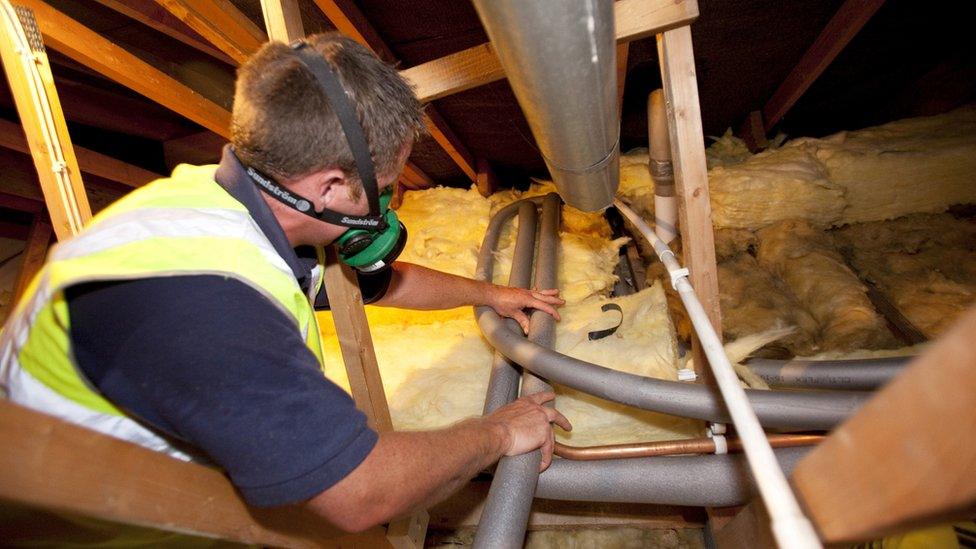 Worker installing loft insulation