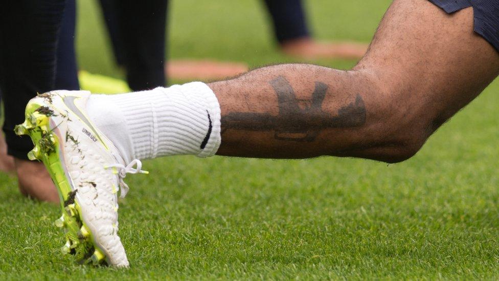 England's midfielder Raheem Sterling displays a tattoo of an assault rifle on his lower leg during a training session at St George's Park in Burton-on-Trent on May 28, 2018