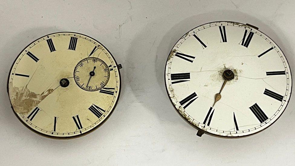 Two 19th Century watch faces. The one on the left is cream coloured and slightly smaller than the one on the right.  It also has a much smaller second hand face. The one on the right is whiter in colour. 