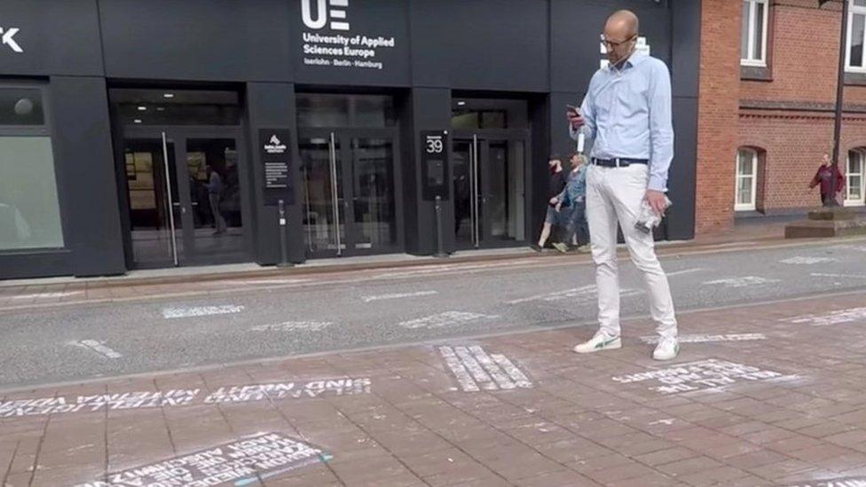 A man takes pictures of "hate tweets", a part of the art project "#HEYTWITTER" created by Shahak Shapira, outside Twitter office in Hamburg, Germany August 4, 2017