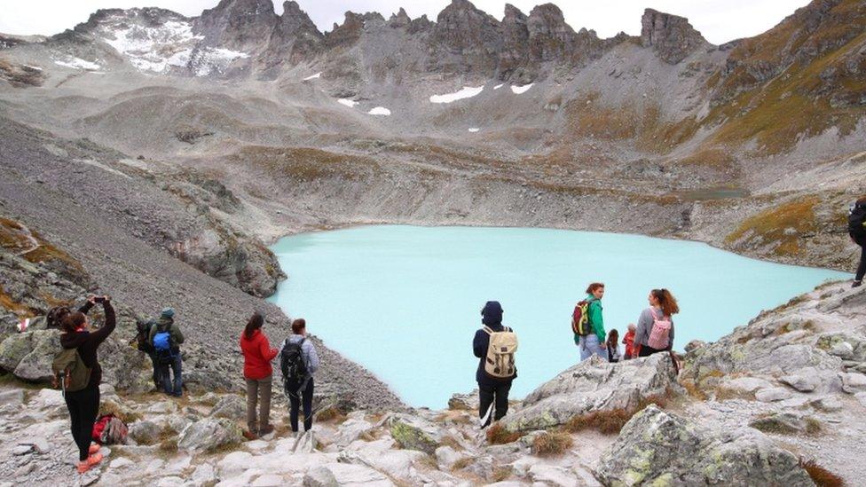 People look at the Pizol glacier as they take part in a mourning ceremony