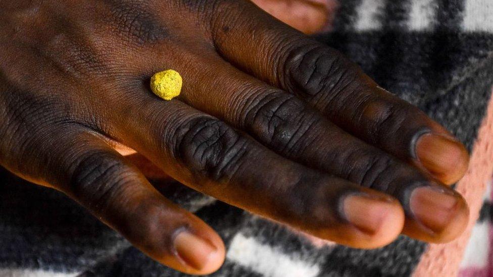 A woman holds raw gold on her hand at a mine