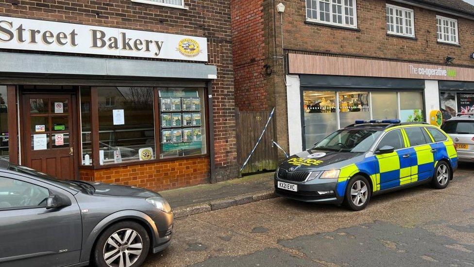 Crime scene taped off across a gateway between two shops