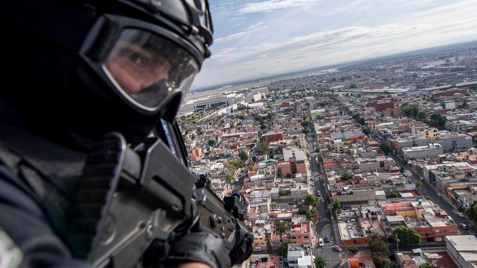 A policeman is seen on board a helicopter as it flies over Mexico City in 2018