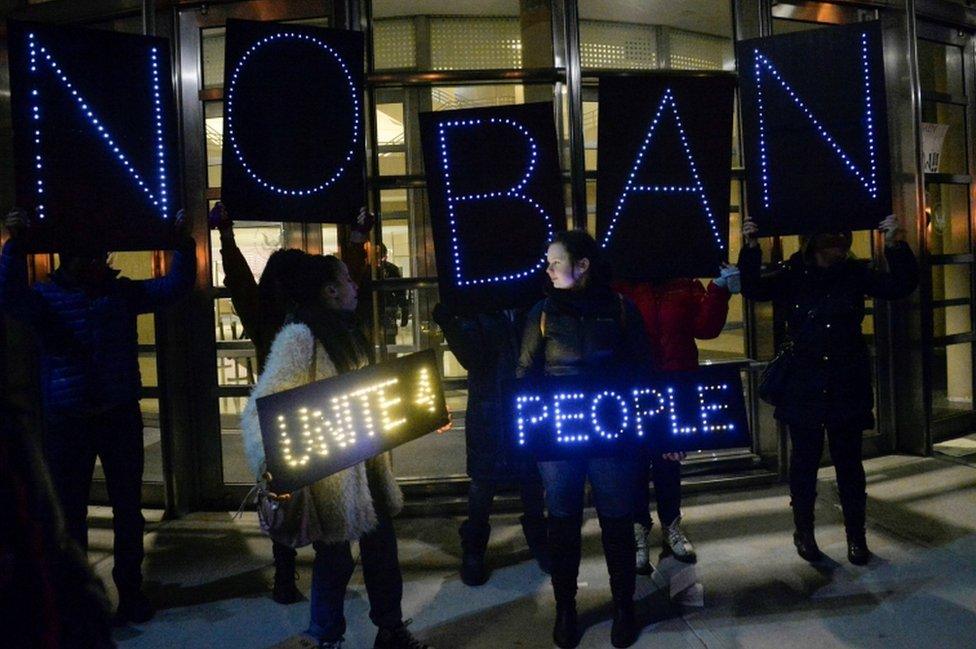 Activists hold placards outside the New York Courthouse where a judge issued an emergency stay blocking the US from sending people out of the country after they have landed at a US airport with valid visas