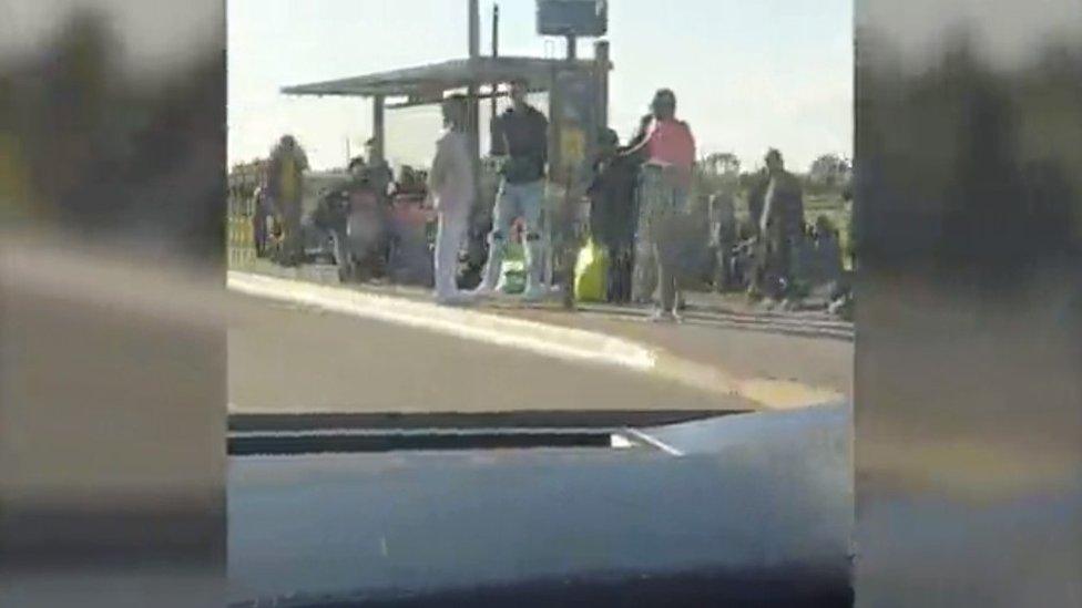 Migrants waiting for a bus to the beach